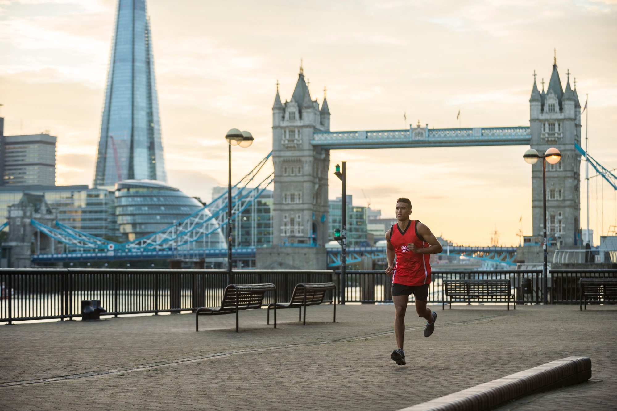 Man running by riverside, Tower Bridge and The Shard in background, Wapping, London, UK